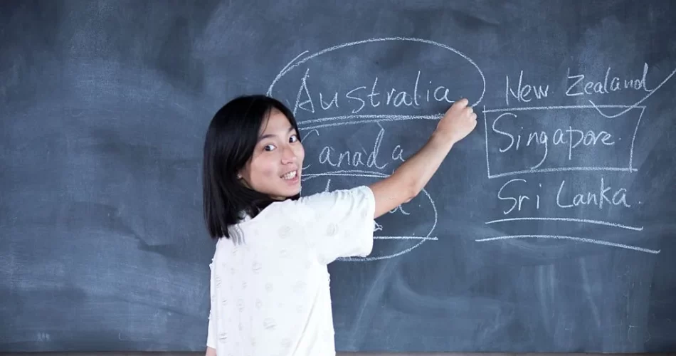 Japanese female English teacher writing on the black board using a white chalk